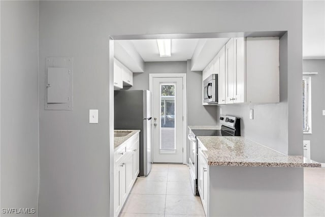 kitchen with light tile patterned floors, stainless steel appliances, light stone counters, white cabinets, and kitchen peninsula