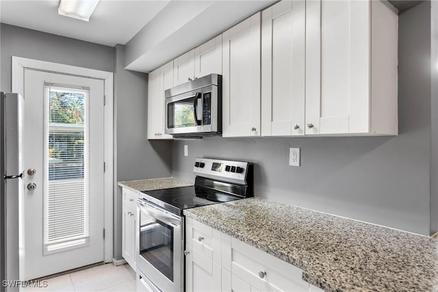 kitchen with light stone counters, stainless steel appliances, and white cabinets