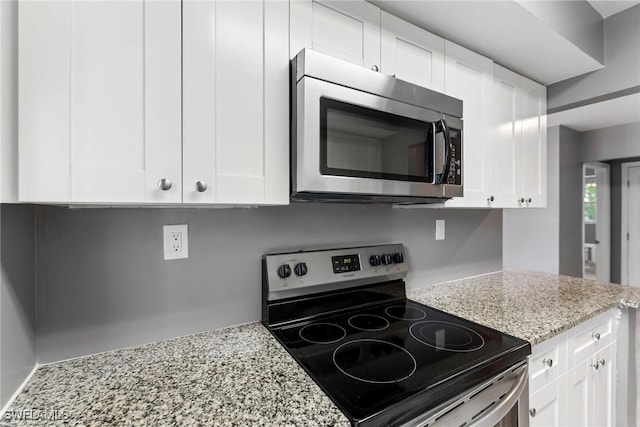 kitchen featuring white cabinetry, stainless steel appliances, and light stone counters