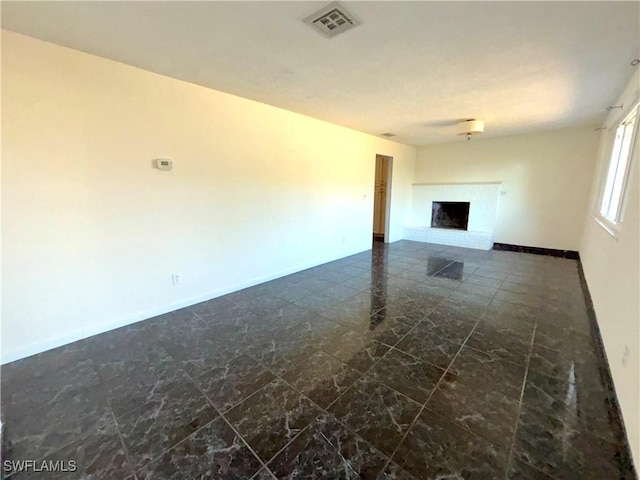 unfurnished living room featuring marble finish floor, a brick fireplace, visible vents, and baseboards