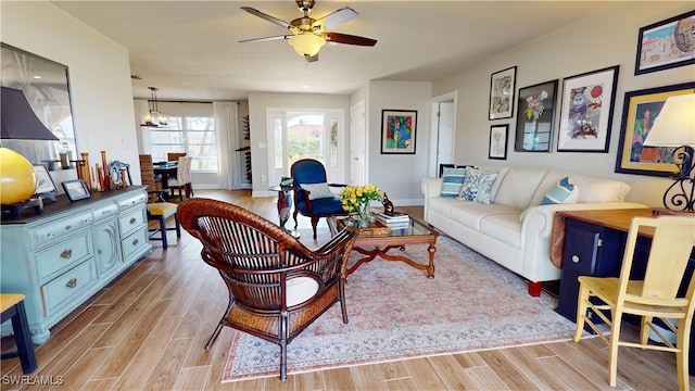 living room with ceiling fan with notable chandelier and light wood-type flooring