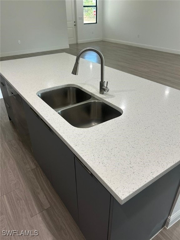 kitchen with light stone counters, sink, and dark hardwood / wood-style floors