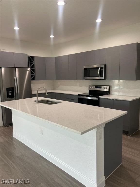 kitchen with stainless steel appliances, sink, a center island with sink, and gray cabinetry