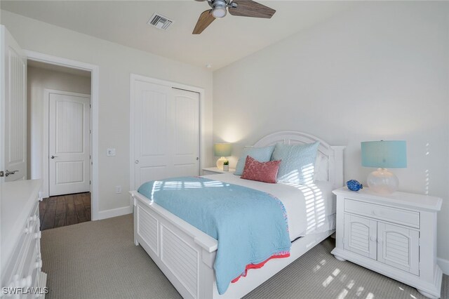 bedroom with a closet, dark colored carpet, and ceiling fan