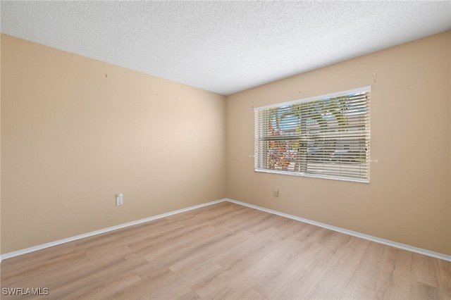 unfurnished room with a textured ceiling and light wood-type flooring