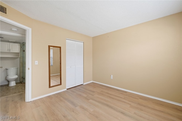 unfurnished bedroom featuring a closet, light hardwood / wood-style flooring, and a textured ceiling