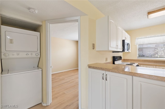 kitchen featuring electric stove, light hardwood / wood-style flooring, white cabinetry, stacked washer and clothes dryer, and a textured ceiling