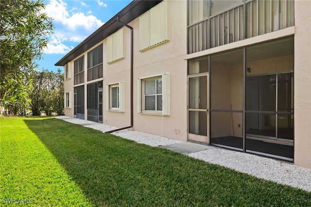 rear view of property featuring a yard and a sunroom