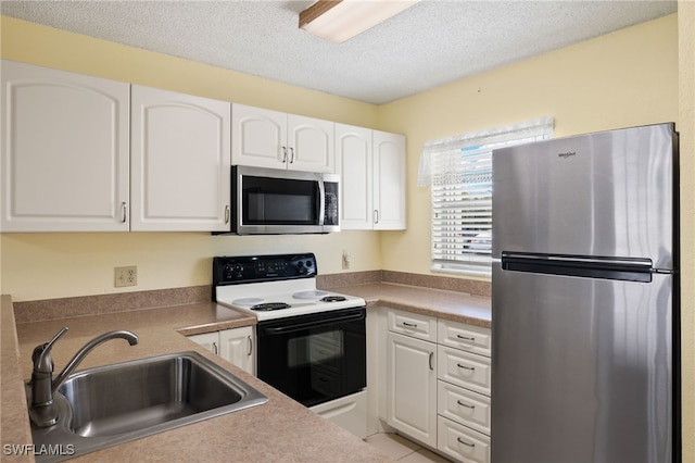 kitchen featuring sink, a textured ceiling, light tile patterned floors, appliances with stainless steel finishes, and white cabinets