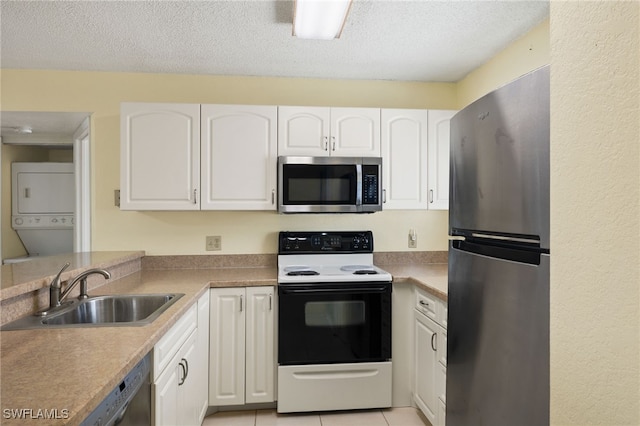 kitchen with stacked washer and dryer, white cabinetry, appliances with stainless steel finishes, and sink