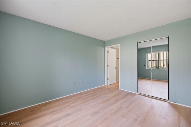 unfurnished bedroom with light hardwood / wood-style floors, a closet, and a textured ceiling