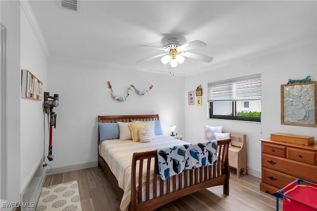 bedroom featuring ceiling fan, ornamental molding, and light wood-type flooring