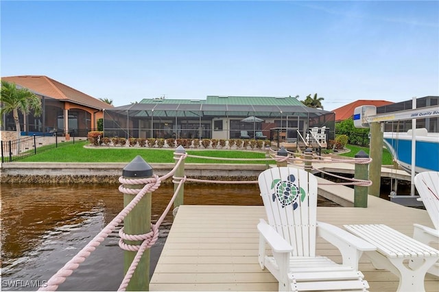 dock area with a lawn, a water view, and glass enclosure