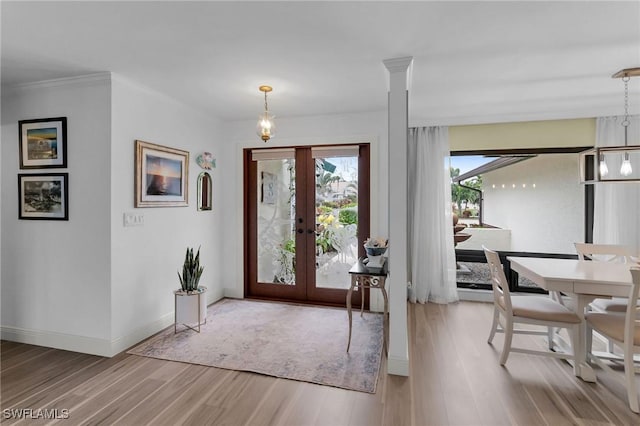 foyer featuring hardwood / wood-style floors, crown molding, decorative columns, and french doors