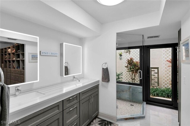 bathroom featuring a shower with door and vanity