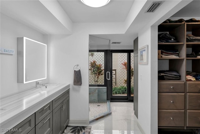 bathroom featuring a shower with door and vanity