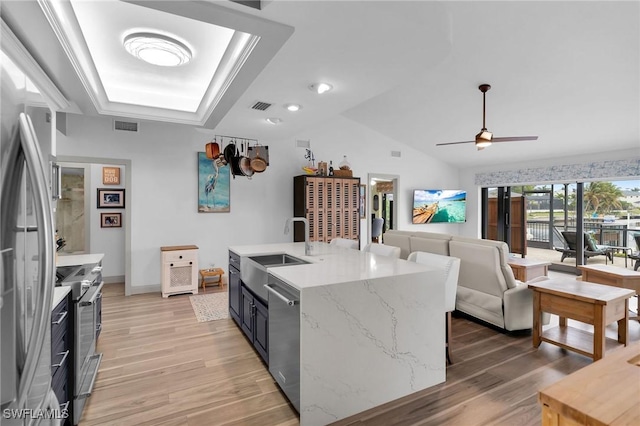 kitchen with a kitchen island with sink, sink, stainless steel appliances, and light wood-type flooring