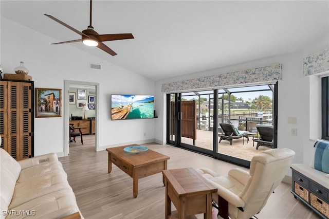 living room with ceiling fan, vaulted ceiling, and light wood-type flooring