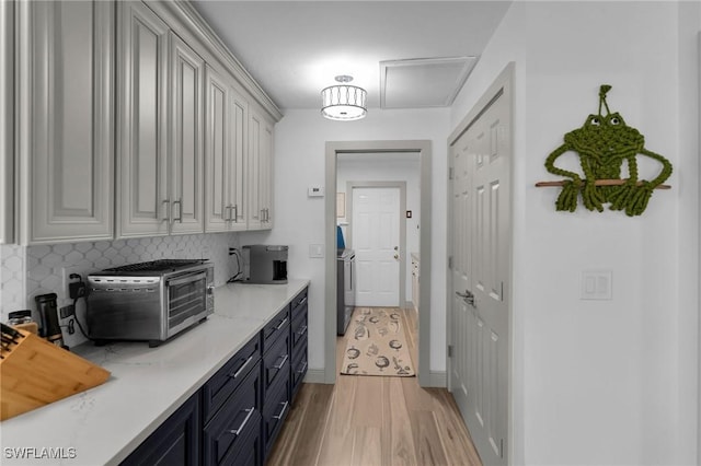 kitchen with gray cabinetry, backsplash, and light hardwood / wood-style flooring