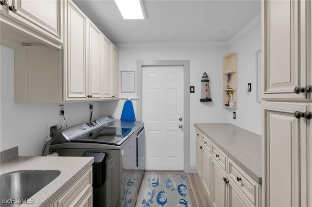 clothes washing area featuring sink, crown molding, cabinets, light hardwood / wood-style floors, and separate washer and dryer