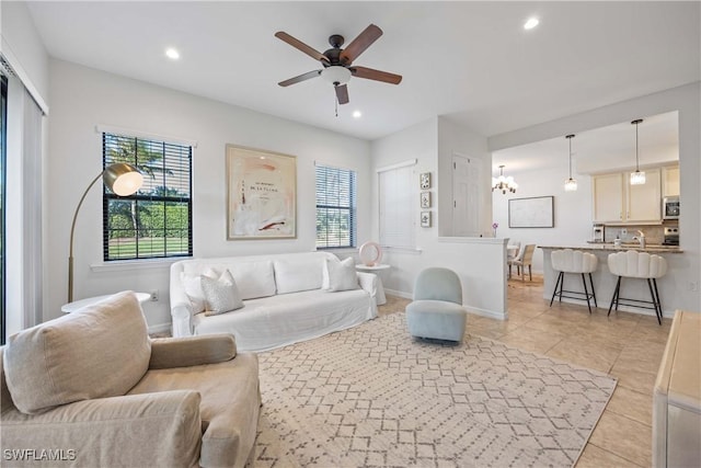 living room with light tile patterned flooring, ceiling fan with notable chandelier, and a wealth of natural light