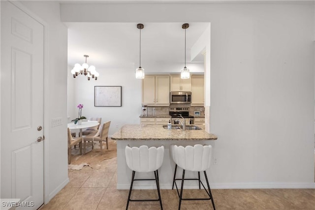 kitchen with pendant lighting, a kitchen bar, decorative backsplash, stainless steel appliances, and light stone countertops