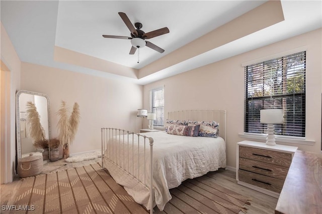 bedroom featuring a tray ceiling, light hardwood / wood-style floors, and ceiling fan