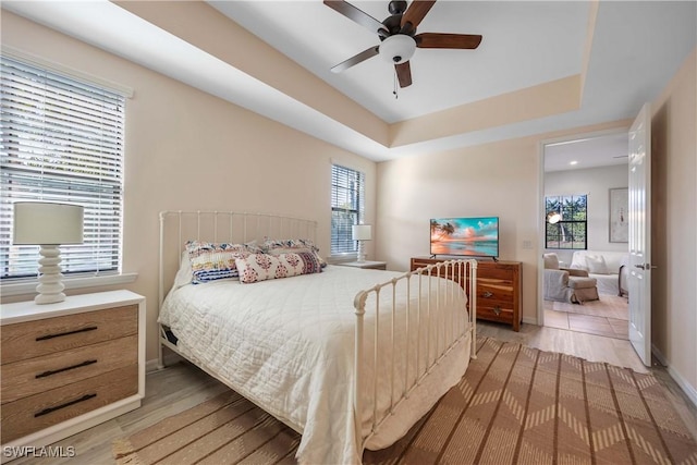 bedroom featuring hardwood / wood-style flooring, ceiling fan, and a tray ceiling