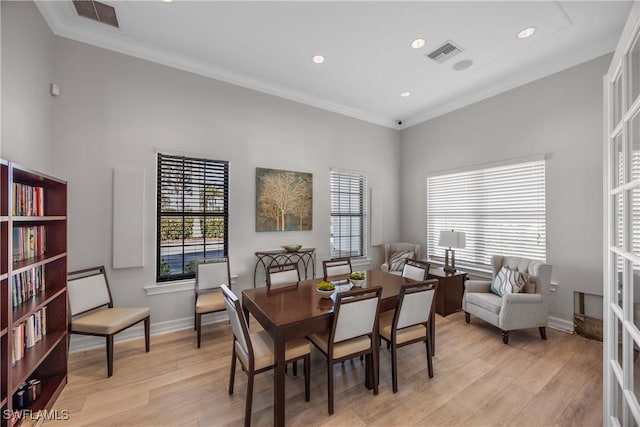 dining area with ornamental molding and light hardwood / wood-style floors