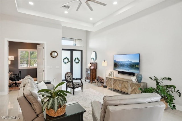 living room featuring light tile patterned flooring, french doors, a raised ceiling, a towering ceiling, and ceiling fan