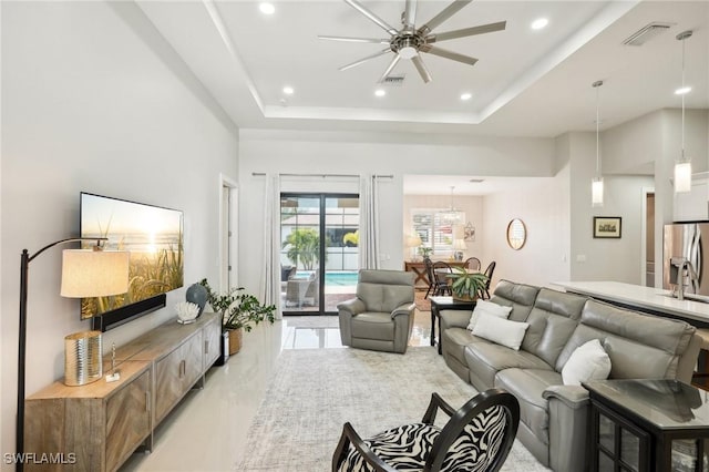 living room featuring a raised ceiling and ceiling fan