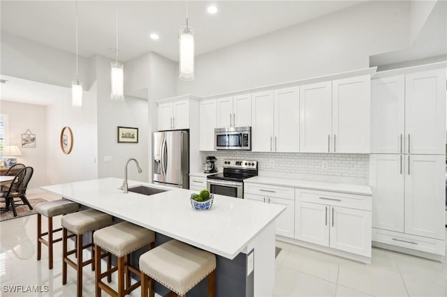 kitchen featuring stainless steel appliances, a kitchen island with sink, sink, and white cabinets