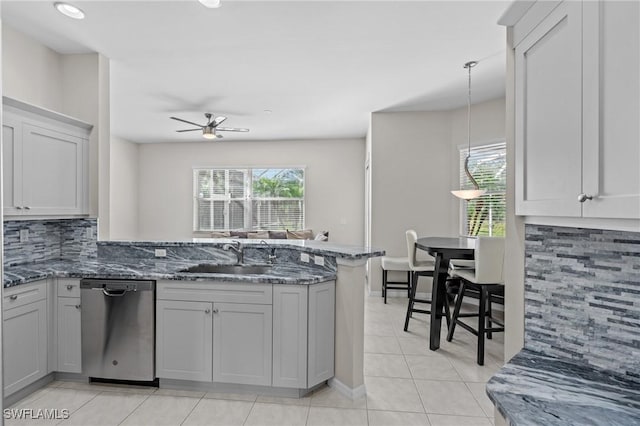 kitchen with dishwasher, dark stone countertops, backsplash, decorative light fixtures, and kitchen peninsula