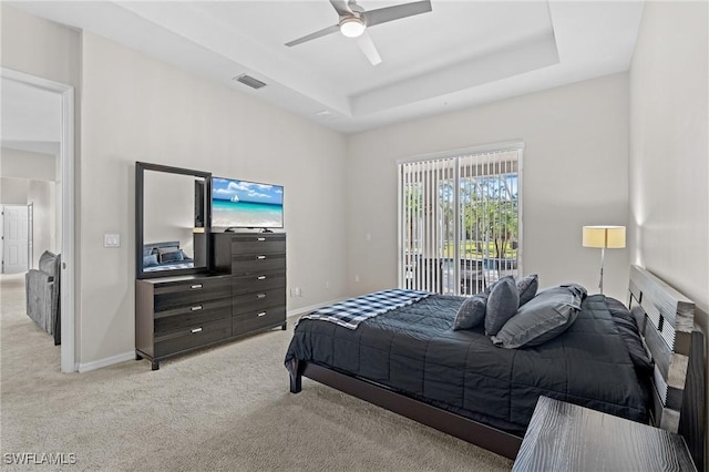 bedroom with light carpet, access to exterior, a tray ceiling, and ceiling fan