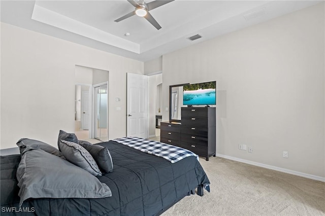 bedroom with light carpet, a tray ceiling, and ceiling fan