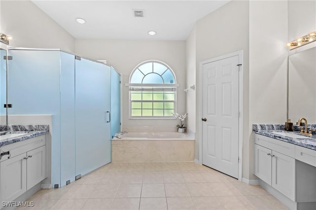 bathroom featuring tile patterned floors, vanity, and tiled tub