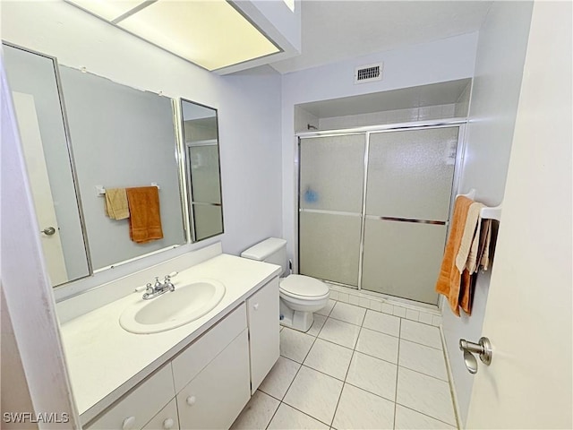 bathroom featuring an enclosed shower, vanity, tile patterned floors, and toilet