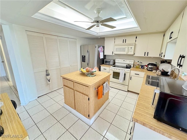 kitchen with light tile patterned flooring, a kitchen island, wood counters, sink, and white appliances