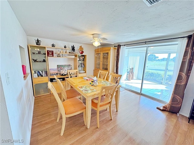 dining room with ceiling fan, hardwood / wood-style floors, and a textured ceiling