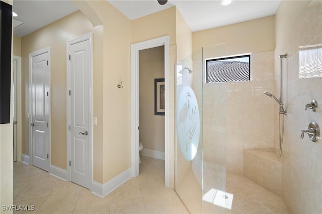 bathroom with a tile shower, tile patterned flooring, and toilet