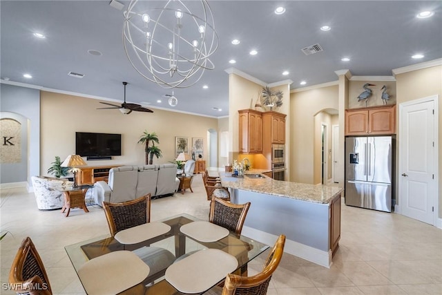 tiled dining space featuring ornamental molding, sink, and ceiling fan