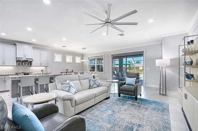 living room with light tile patterned flooring, ceiling fan, and crown molding