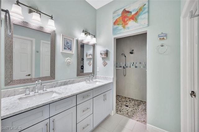 bathroom with tiled shower, vanity, and tile patterned flooring