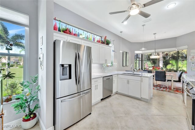 kitchen featuring appliances with stainless steel finishes, pendant lighting, sink, white cabinets, and kitchen peninsula