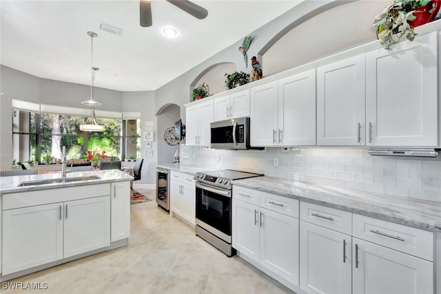 kitchen with wine cooler, sink, white cabinetry, appliances with stainless steel finishes, and light stone countertops