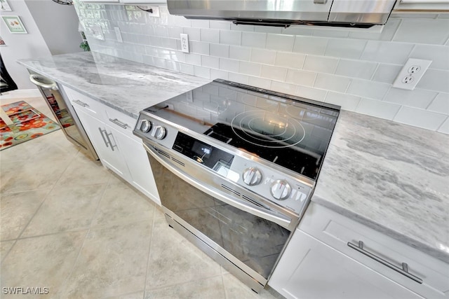 kitchen featuring light tile patterned flooring, stainless steel range with electric cooktop, light stone counters, white cabinets, and backsplash