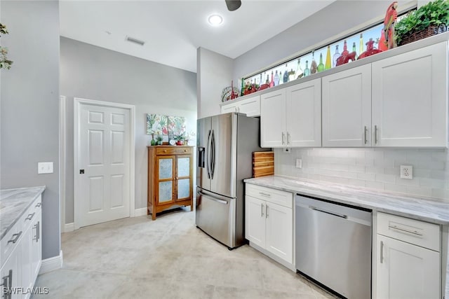 kitchen with tasteful backsplash, stainless steel appliances, light stone countertops, and white cabinets