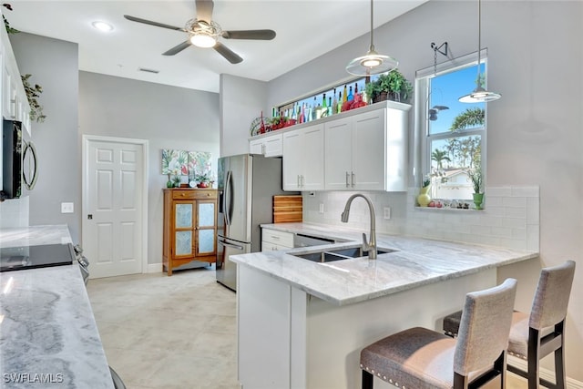 kitchen with sink, white cabinetry, stainless steel appliances, a kitchen breakfast bar, and decorative light fixtures