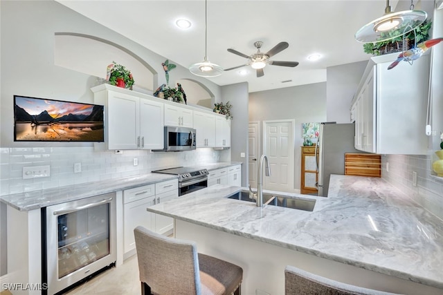 kitchen featuring stainless steel appliances, beverage cooler, sink, and white cabinets