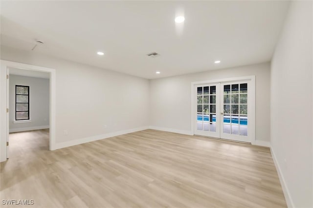 spare room featuring a wealth of natural light, light wood-type flooring, and french doors